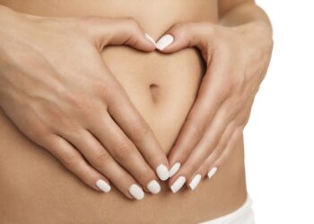 Pregnancy or diet concept, female hands forming heart shape on the stomach