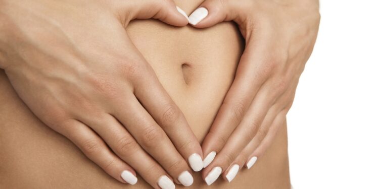 Pregnancy or diet concept, female hands forming heart shape on the stomach